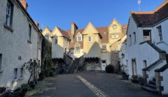 Old courtyard in Edinburgh with very old houses and blue sky above.