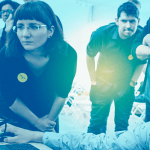 A group of students working collaboratively around a computer, with a blue tint over the image.