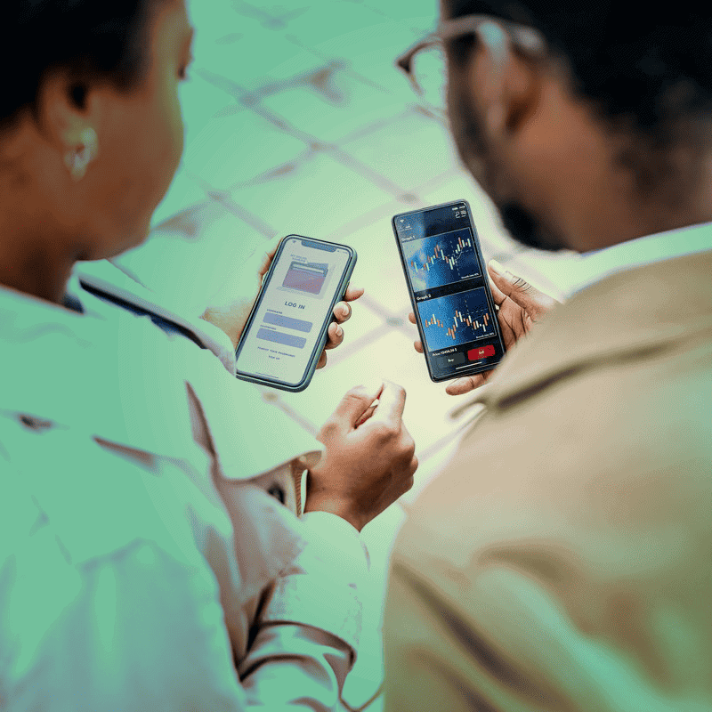 Two people looking at graphs on their phones. green tint over image.