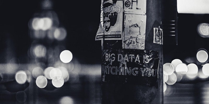 Black and white image of lamppost with posters on it.