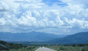 Long road running into distance under blue cloudy sky