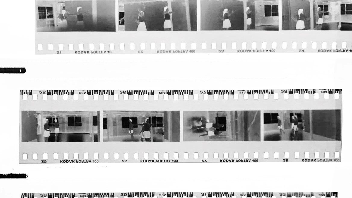 Black and white photo negative strips showing multiple images of people in domestic settings, including kitchen scenes. The negatives are from a Kodak Safety Film roll.